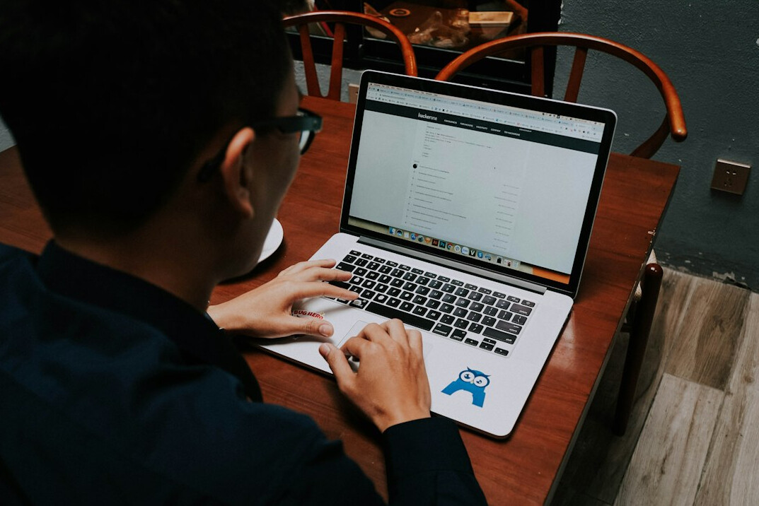 student coding on laptop with notebook